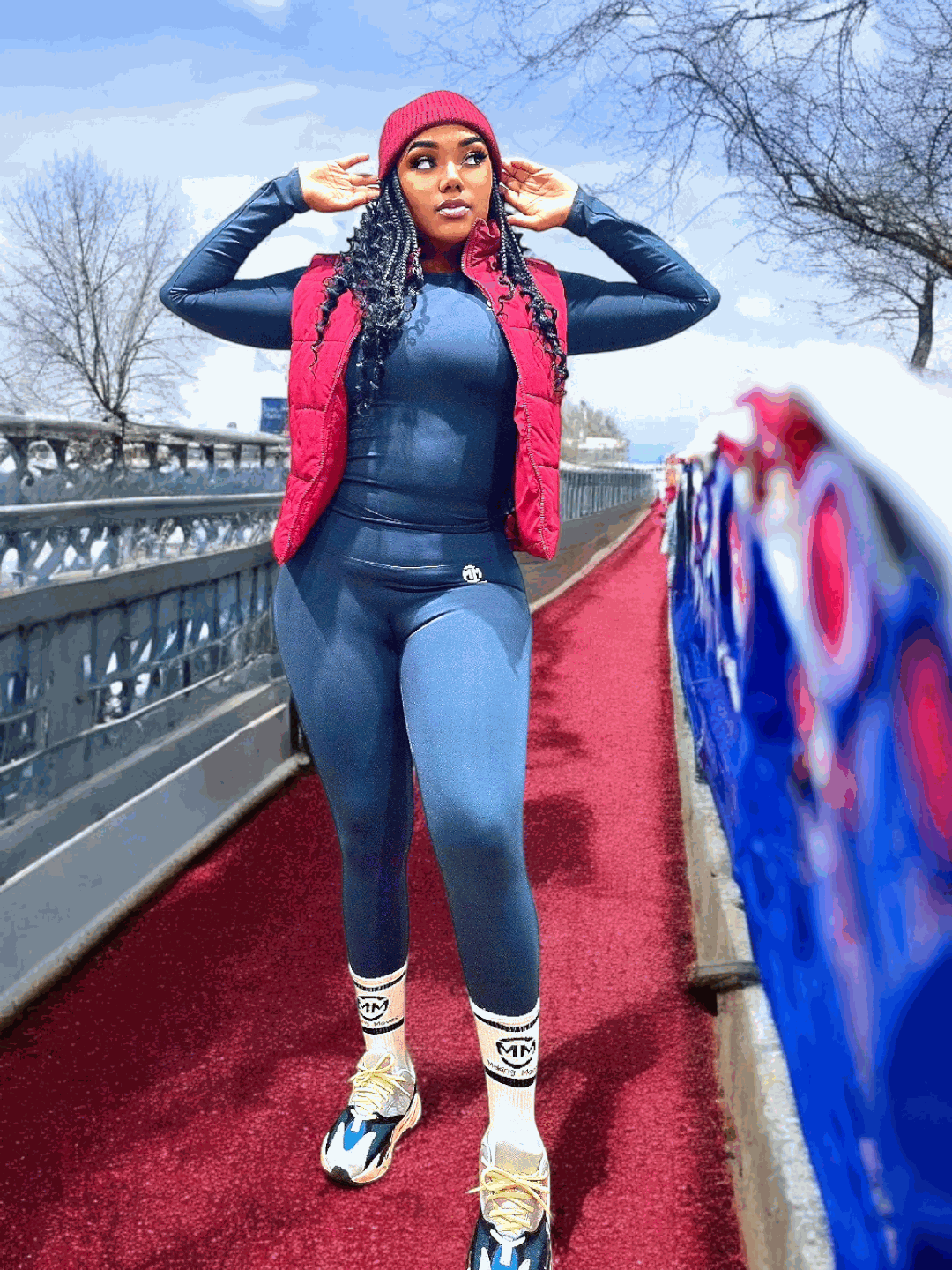 Woman wearing Chill & Conquer Lounge Set in navy with red vest and athletic shoes outdoors on a bridge
