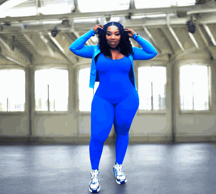 Bright blue POWER SLEEVELESS JUMPSUIT worn in fitness setting with V-shaped scrunch back design.