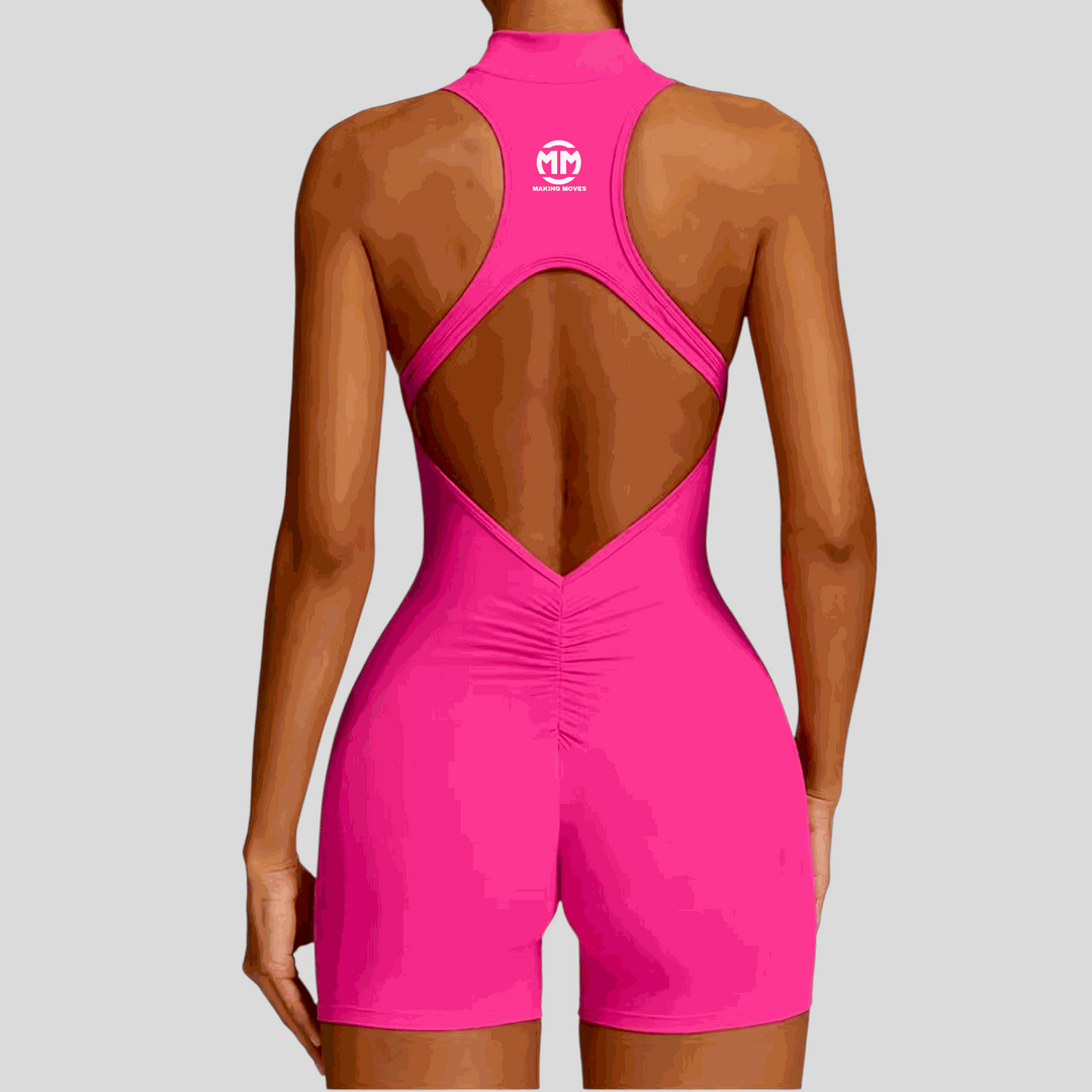 Back view of woman wearing bright pink Pixie Playsuit 2.0 with hollow back and sleeveless design.